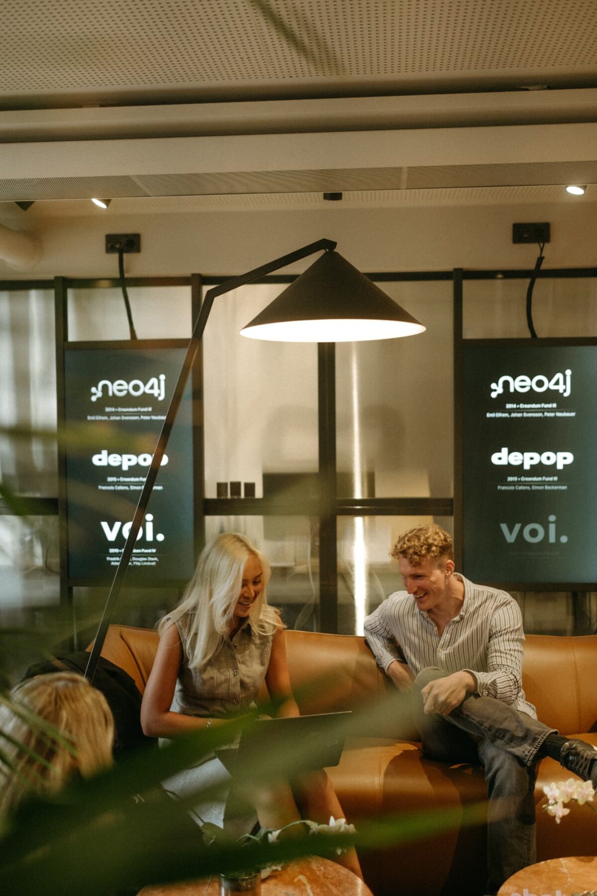Creandum team members working together on a sofa beneath portfolio screens